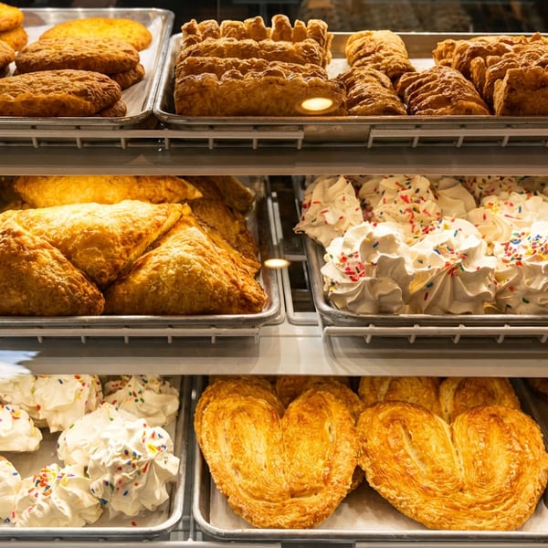 Assorted baked goods, including cookies, pastries, and meringue cookies with sprinkles, in a display case.
