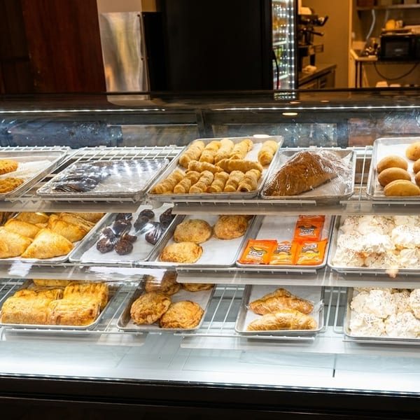 A refrigerated bakery display case filled with various pastries, cookies, and meringues on multiple shelves.